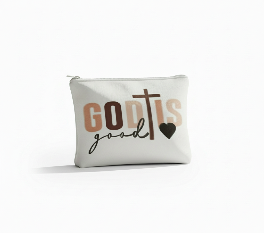 White pouch with 'God is Good' text on a wooden table with books and a plant.